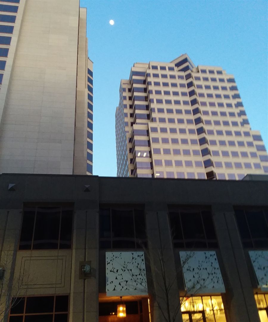 The moon visible between the two towers of the Hyatt Hotel in Downtown Albuquerque at Third street and Tijeras Street. This photo was taken on the other side of 4th street which is west of the towers. These are 2 of the tallest towers in Albuquerque. This is easily accomplished because there are only about 12 skyscrapers in Albuquerque and most new buildings are only 7-8 stories tall, at the highest.