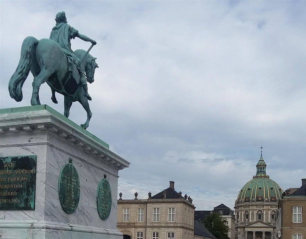A second view from the center of Amalienborg Palace courtyard with the equistrian statue with King Fredrik V in the forground and Fredricks'Church in the background.